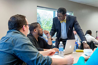 Professor in classroom environment speaking to two students